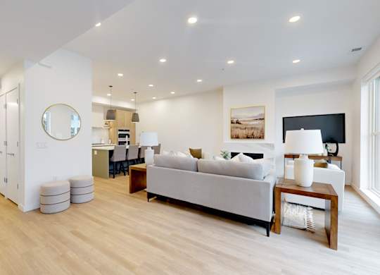 A modern living room with a grey sofa and wooden floors.