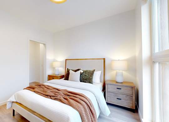 A bedroom with a bed, nightstand, and lamp.