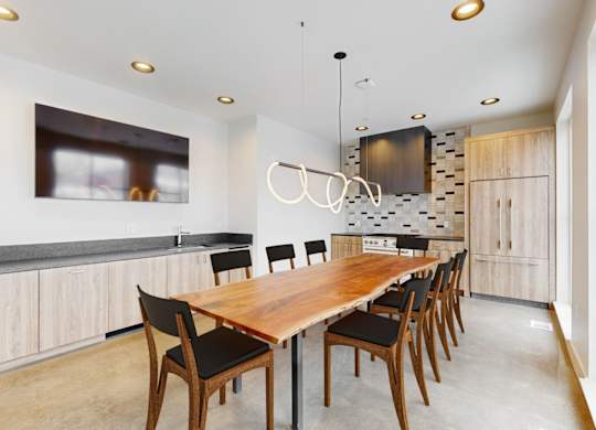 A long wooden table is surrounded by chairs in a modern room.