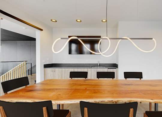 A modern dining room with a wooden table and black chairs.