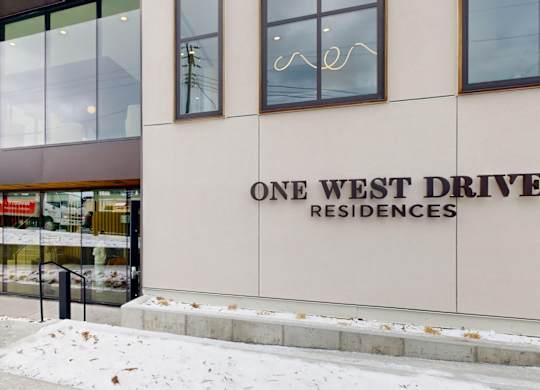 A building with a glass facade and a sign that reads "One West Drive Residences.".
