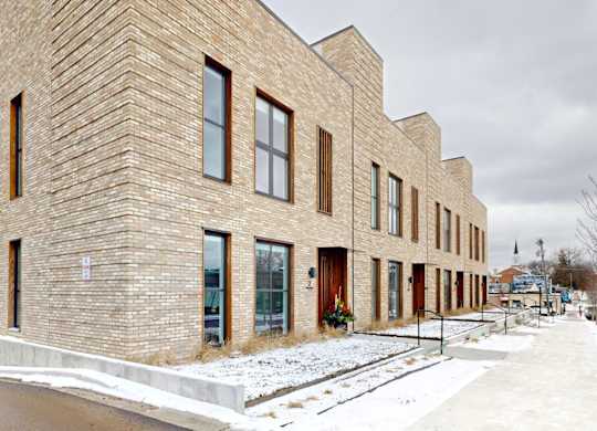 A row of modern brick houses with snow on the ground.