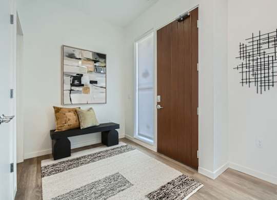 a hallway with a door to a room with a couch and a bench at One West Drive Apartments, Excelsior, MN 55331