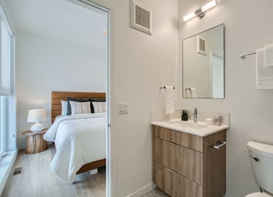 a bedroom with a bed and a bathroom with a toilet and a sink at One West Drive Apartments, Excelsior