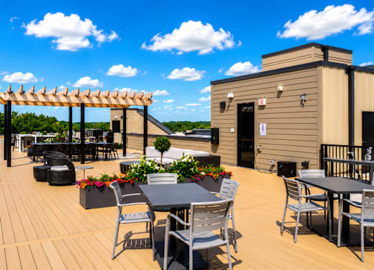 A wooden deck with a table and chairs and a building in the background.