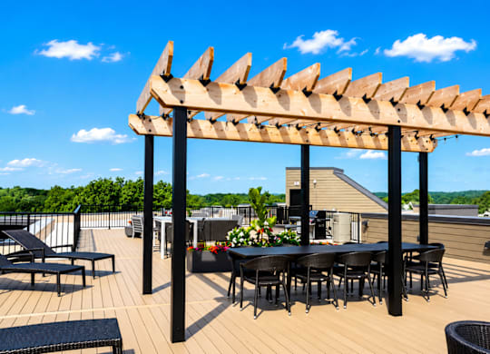 A wooden pergola with a table and chairs underneath it.