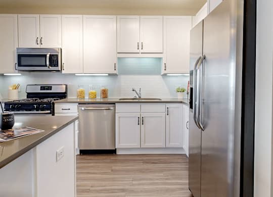 A modern kitchen with white cabinets and stainless steel appliances.