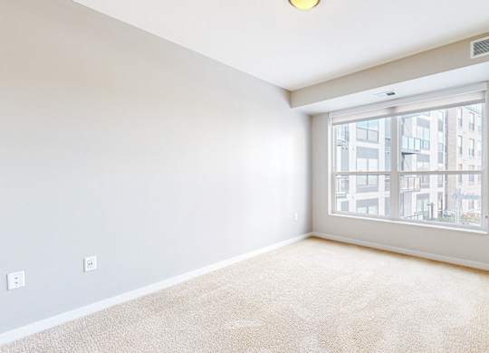 A room with a large window and a carpeted floor.