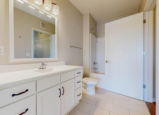 A white bathroom with a sink, toilet, and mirror.