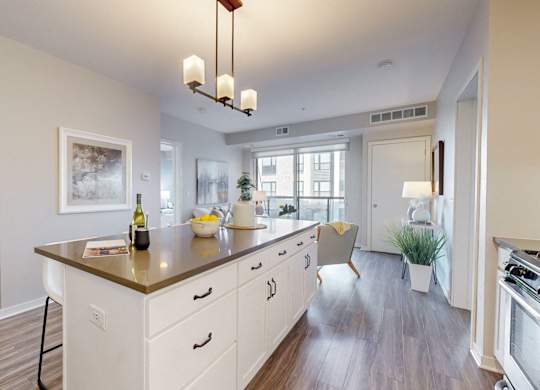 A kitchen with a large island and a dining area in the background.
