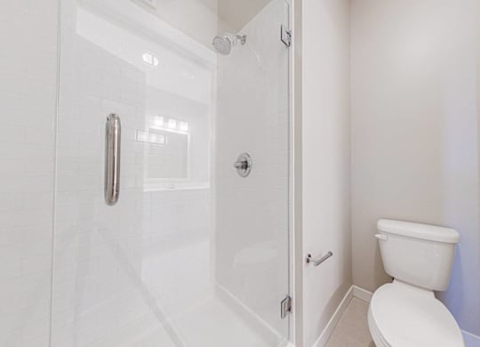 A white toilet in a small bathroom with a glass shower door.