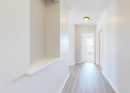 A long white hallway with a door at the end.
