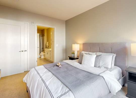 A bedroom with a large bed and a nightstand with a lamp.