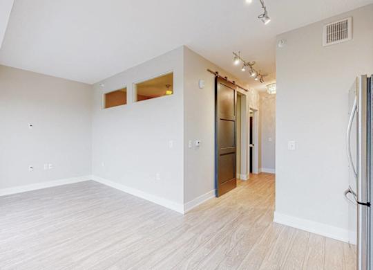 A spacious room with white walls and wooden flooring.