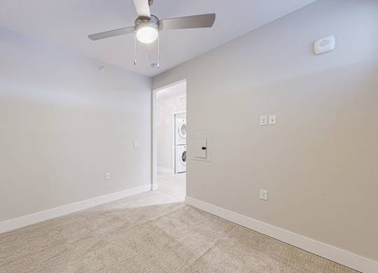 A room with a ceiling fan and carpeted floor.