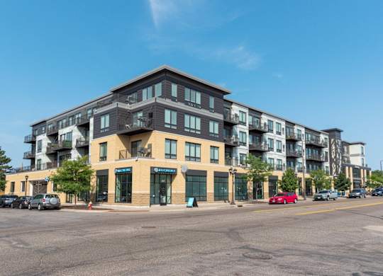 A large apartment building with a parking lot in front.