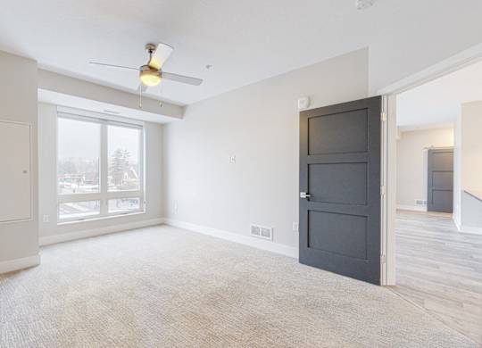 A room with a ceiling fan and a large window.