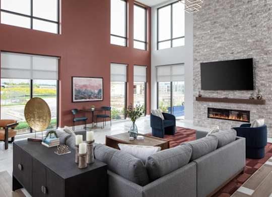 A modern living room with a grey sofa, a fireplace, and a large window.at The Edison at Maple Grove, Minnesota, 55311
