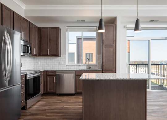 A kitchen with dark brown cabinets and a large island.at The Edison at Maple Grove, Maple Grove Minnesota