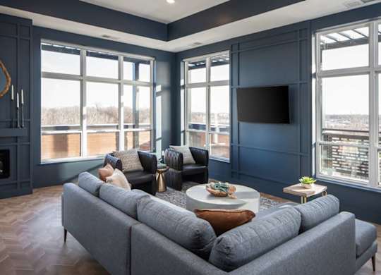A grey couch is in front of a large window in a room with a fireplace.at The Edison at Maple Grove, Maple Grove Minnesota