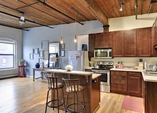 A kitchen with wooden cabinets and a large island with bar stools.at Lee Lofts, Minneapolis, 55401