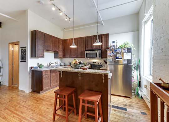 A kitchen with wooden floors and a large island with a bar stool.at Lee Lofts, Minneapolis, MN