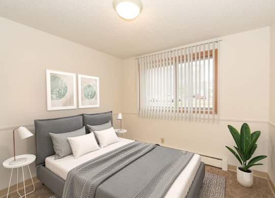 A bedroom with a bed, a plant, and two pictures on the wall.