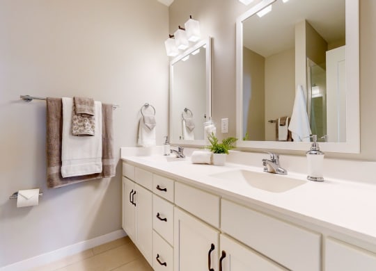a white bathroom with two sinks and a mirror