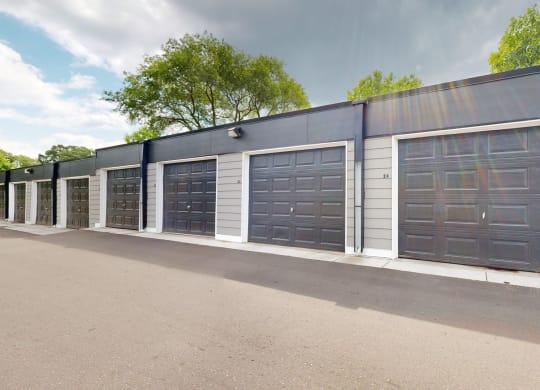 a row of garages in a parking lot with trees in the background