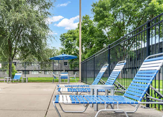 A poolside area with blue lounge chairs and a fence.