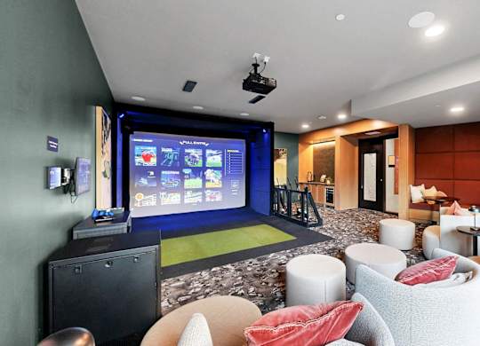 A modern living room with a large screen and comfortable seating.