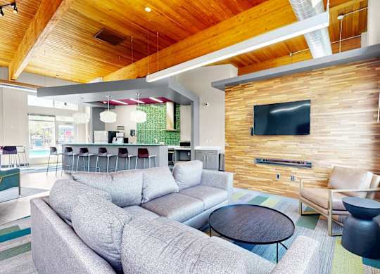 A modern living room with a grey sofa and a wooden wall.