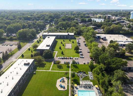 A large building complex with a green lawn and a pool in the foreground.