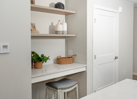 a small kitchenette with a white door and a white stool