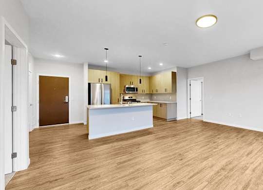 A kitchen with a white countertop and wooden flooring.