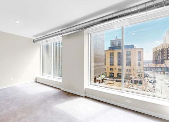 A large empty room with a view of the city outside the window.