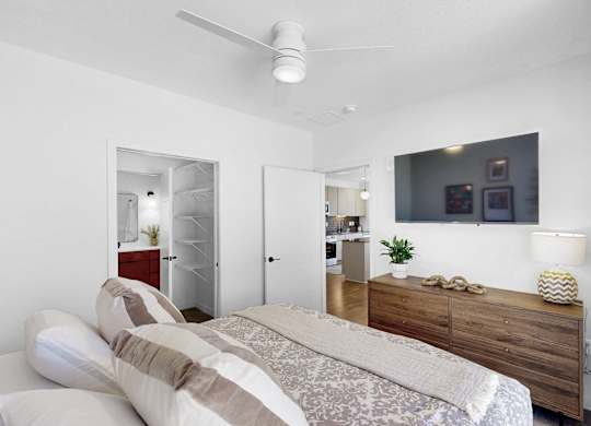 A bedroom with a bed, dresser, and a ceiling fan.