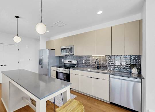 A modern kitchen with a stainless steel island and wooden floors.