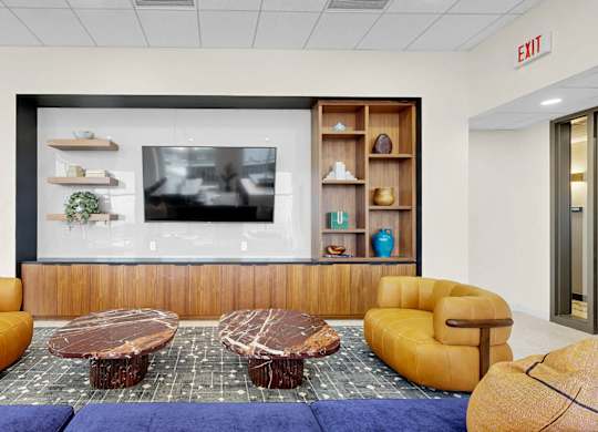 A modern living room with a coffee table in the center and a large screen on the wall.