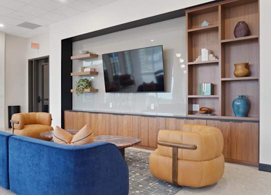 A modern living room with a blue sofa and a television on a wooden stand.