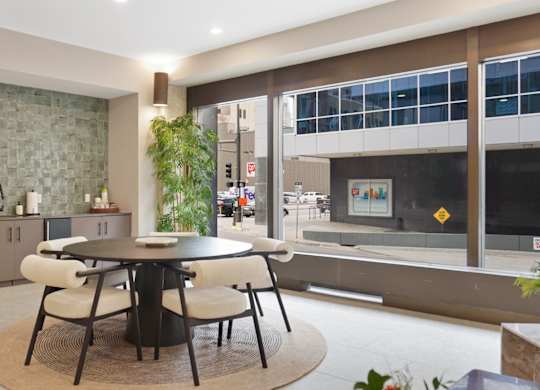 A dining table with chairs is in the middle of a room with a stone wall.
