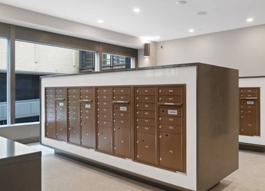 A row of brown mailboxes are lined up on a wall.