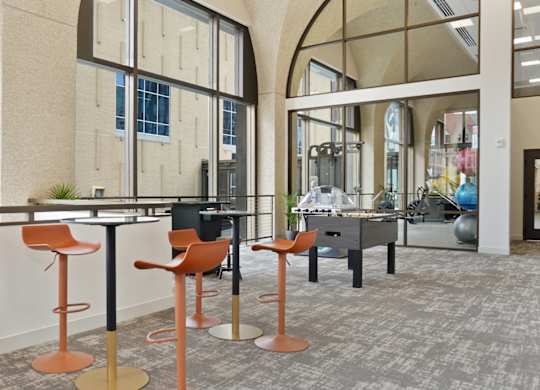 A room with a long table and orange chairs.