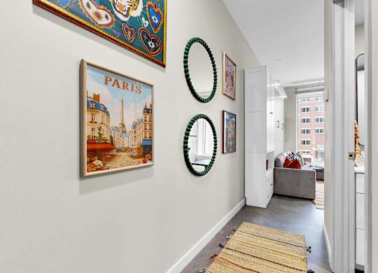 A hallway with a Paris picture on the wall and a round green decoration hanging on it.