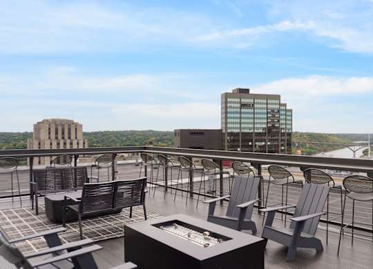 A rooftop patio with chairs and a table overlooking a cityscape.