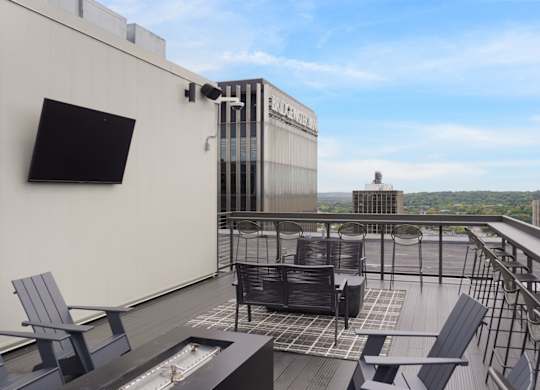 A rooftop patio with chairs and a television.