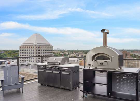 A pizza oven is on a balcony with a view of the city.