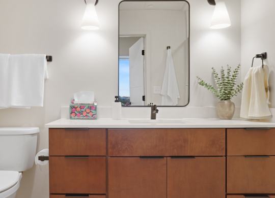 A bathroom with a toilet, sink, and mirror.