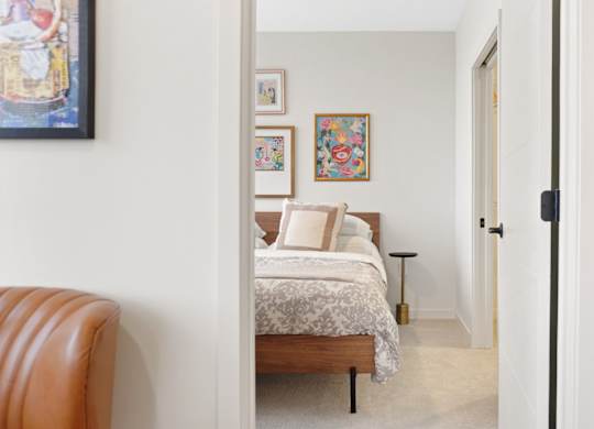A bedroom with a bed, a chair, and pictures on the wall.