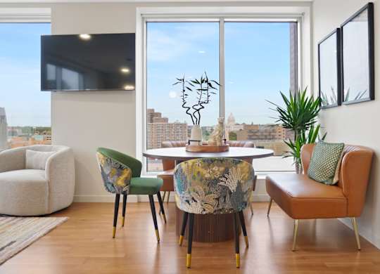 A living room with a large window and a TV on the wall.